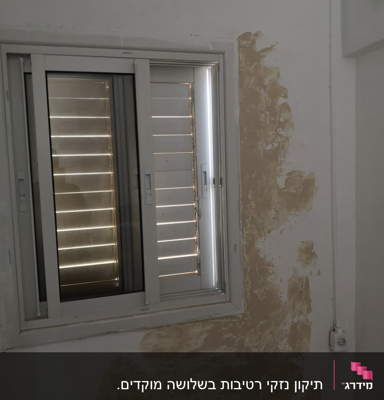 קיר עם טיח מתקלף ליד חלון ותריסים